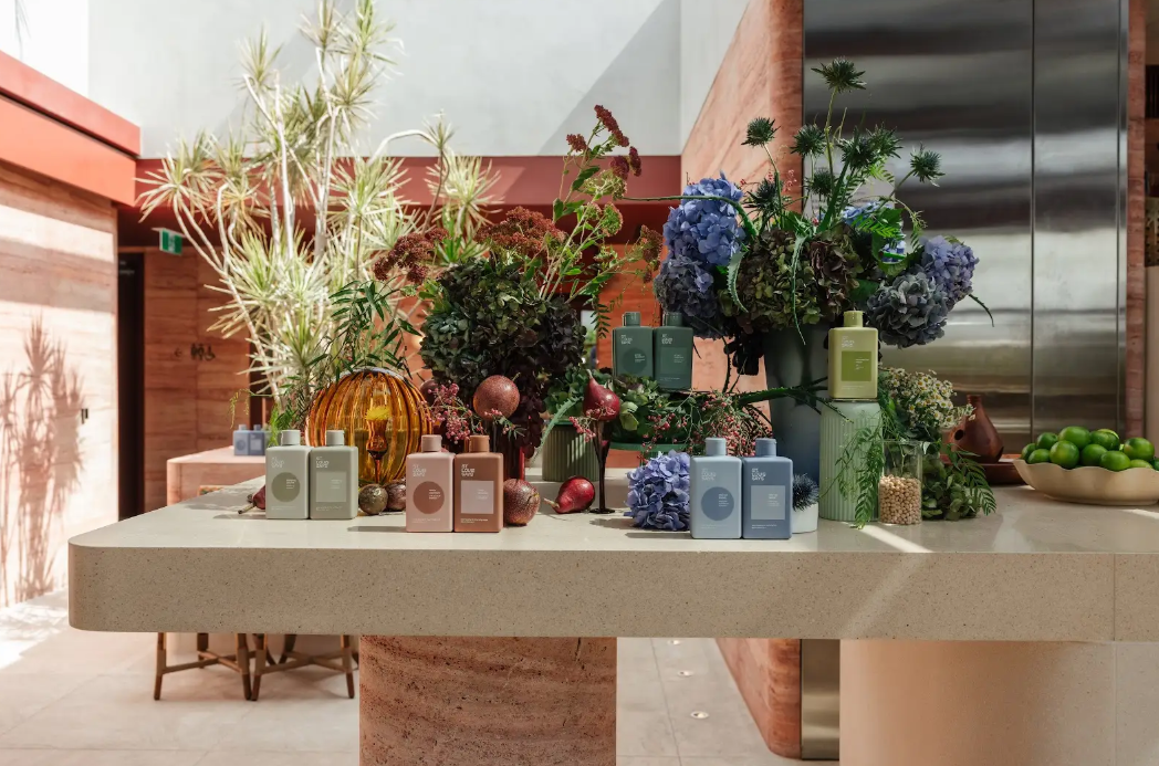 St. Louis Says haircare products styled with botanicals and flowers on a travertine table