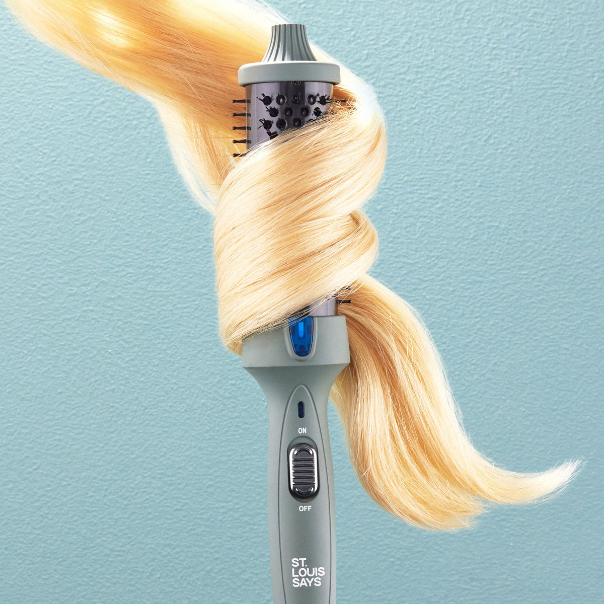 Hair straightener with blonde hair on a light blue background