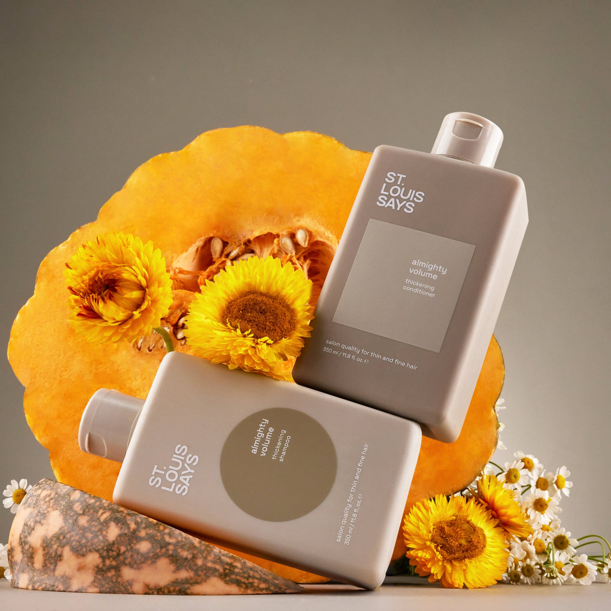 Two bottles of St. Louis Days soap on a decorative pumpkin with yellow flowers.