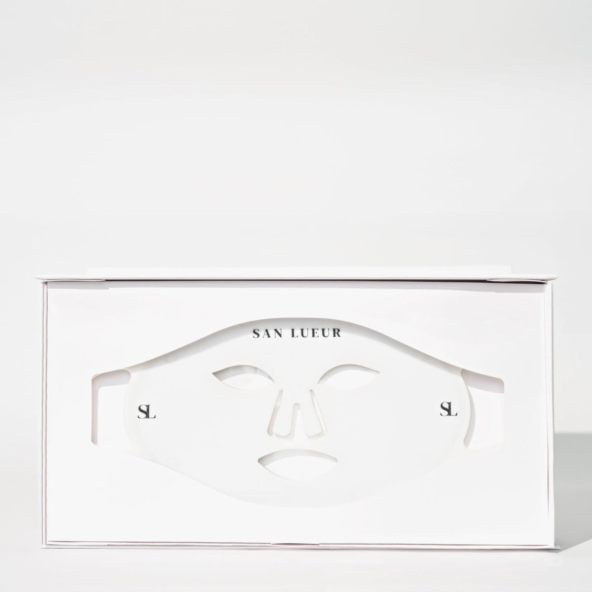 A white SAN LUEUR skincare mask box with a die-cut face mask visible through the front window, photographed on a clean white background.