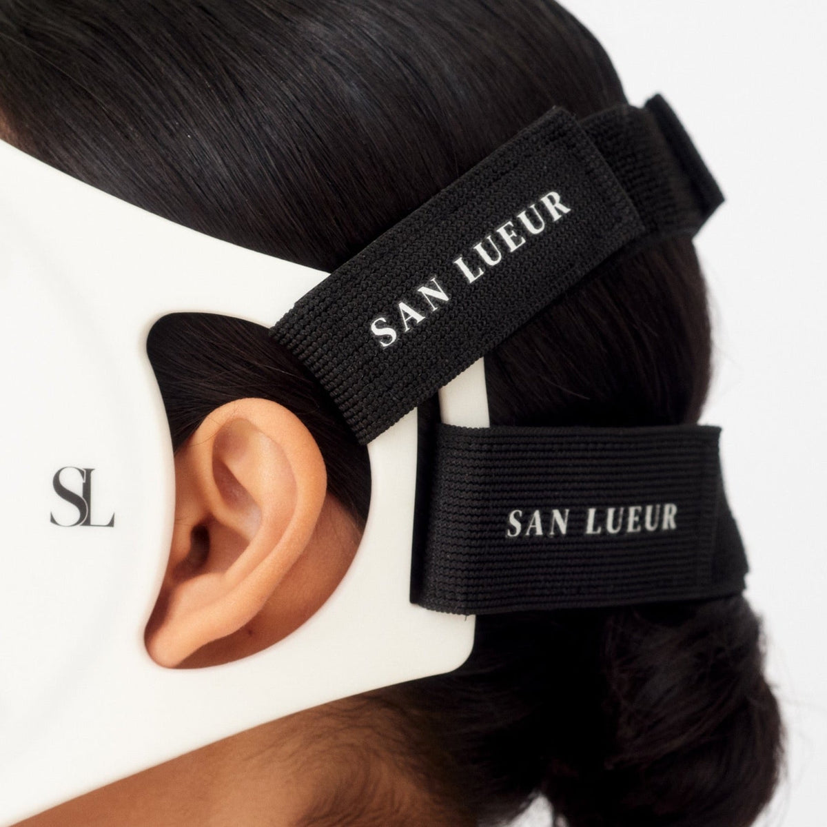 Black hair tie with 'SAN LUEUR' branding worn by a person, close-up view.