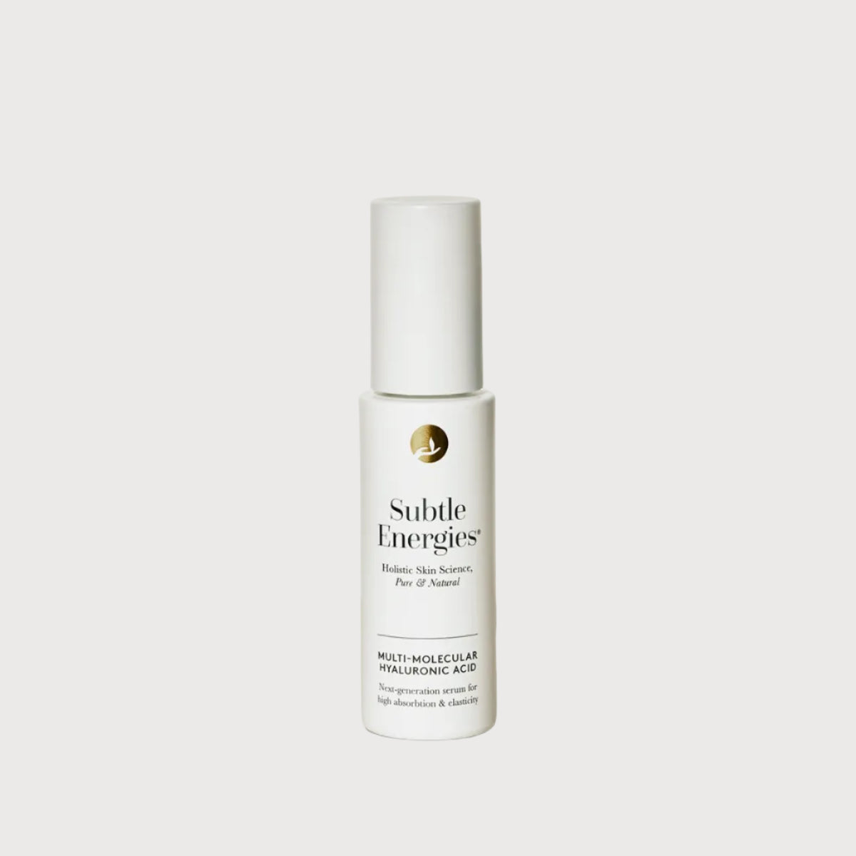 A white bottle of Subtle Energies Multi-Molecular Hyaluronic Acid serum, standing on a light beige surface against a white background with a soft shadow.