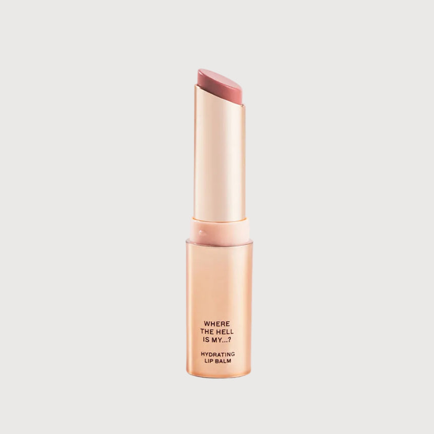 Lip balm with a gold tube and pink cap on a light gray background