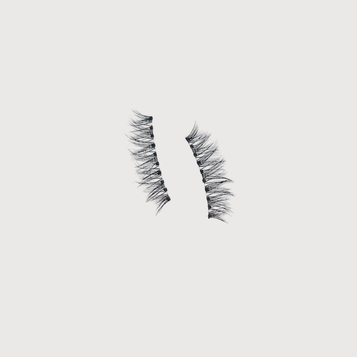Pair of false eyelashes on a light gray background