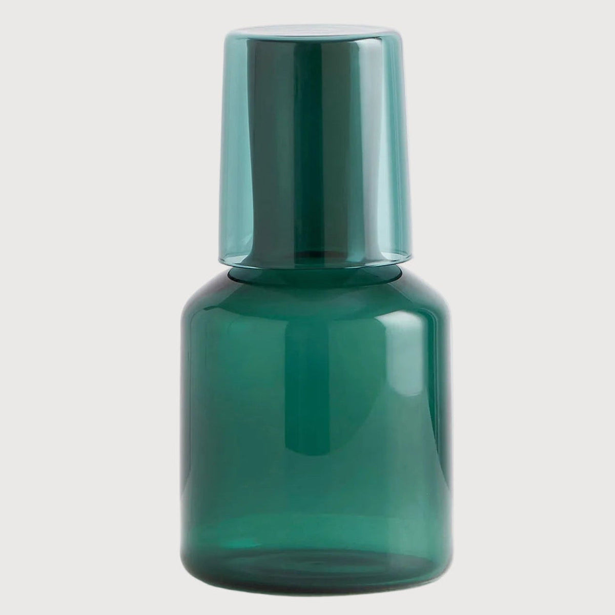 Green glass bottle with a metallic cap on a light gray background