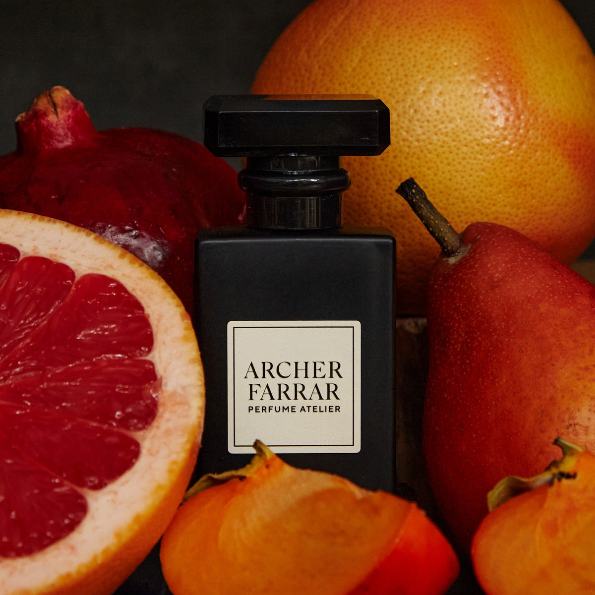 Black Archer Farrar perfume bottle surrounded by fruits on a dark background