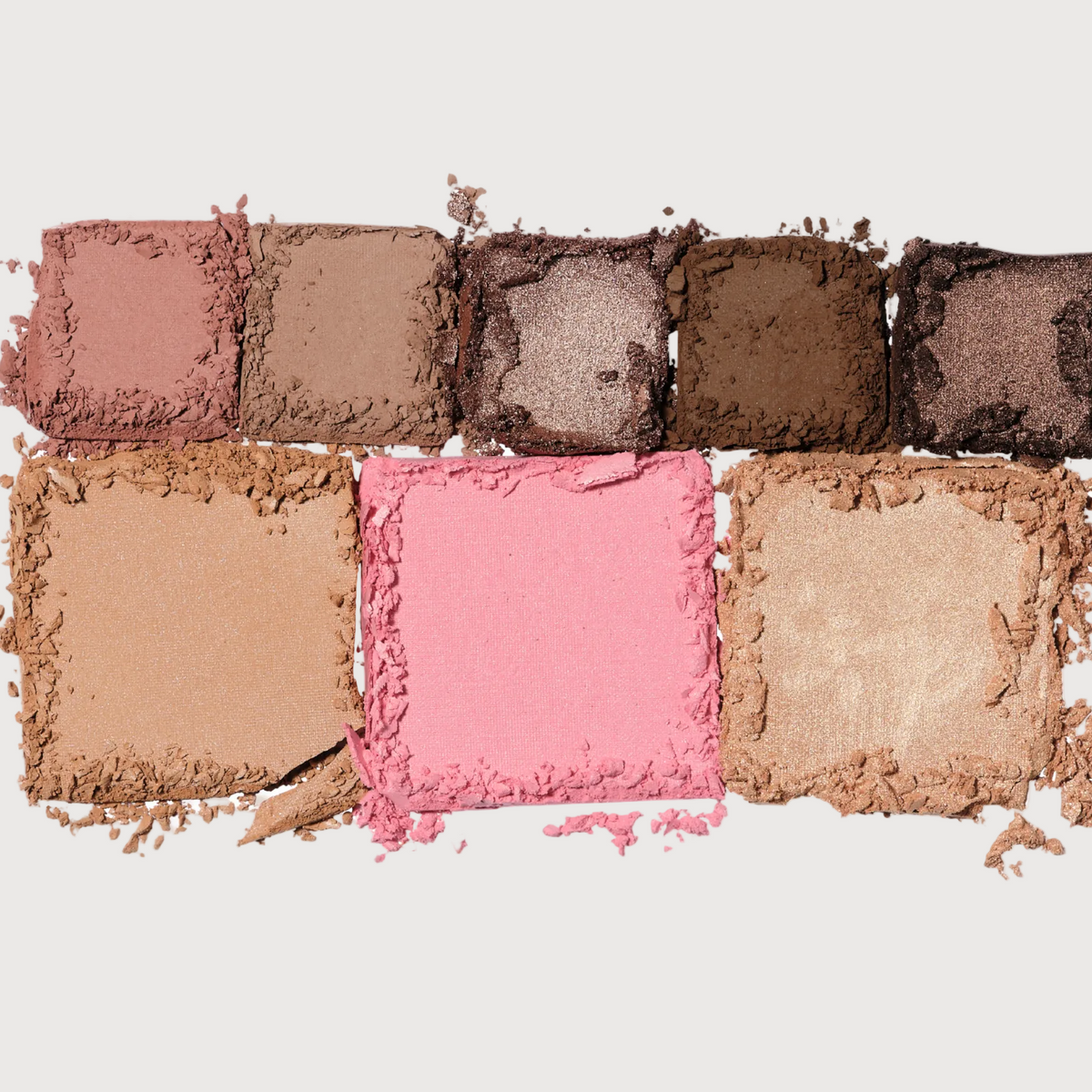 Collection of crushed makeup powders in various colors on a light background