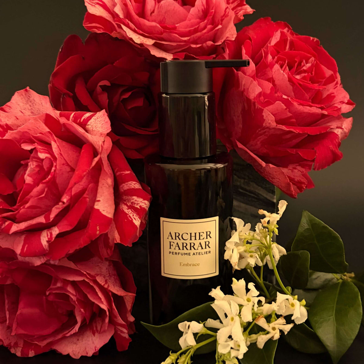 Black bottle with a label surrounded by red roses on a dark background