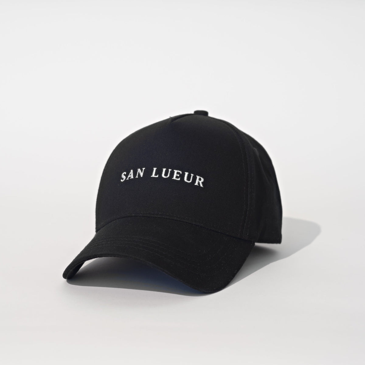 A black baseball cap with 'SAN LUEUR' embroidered in white serif letters on the front, set against a clean white background.