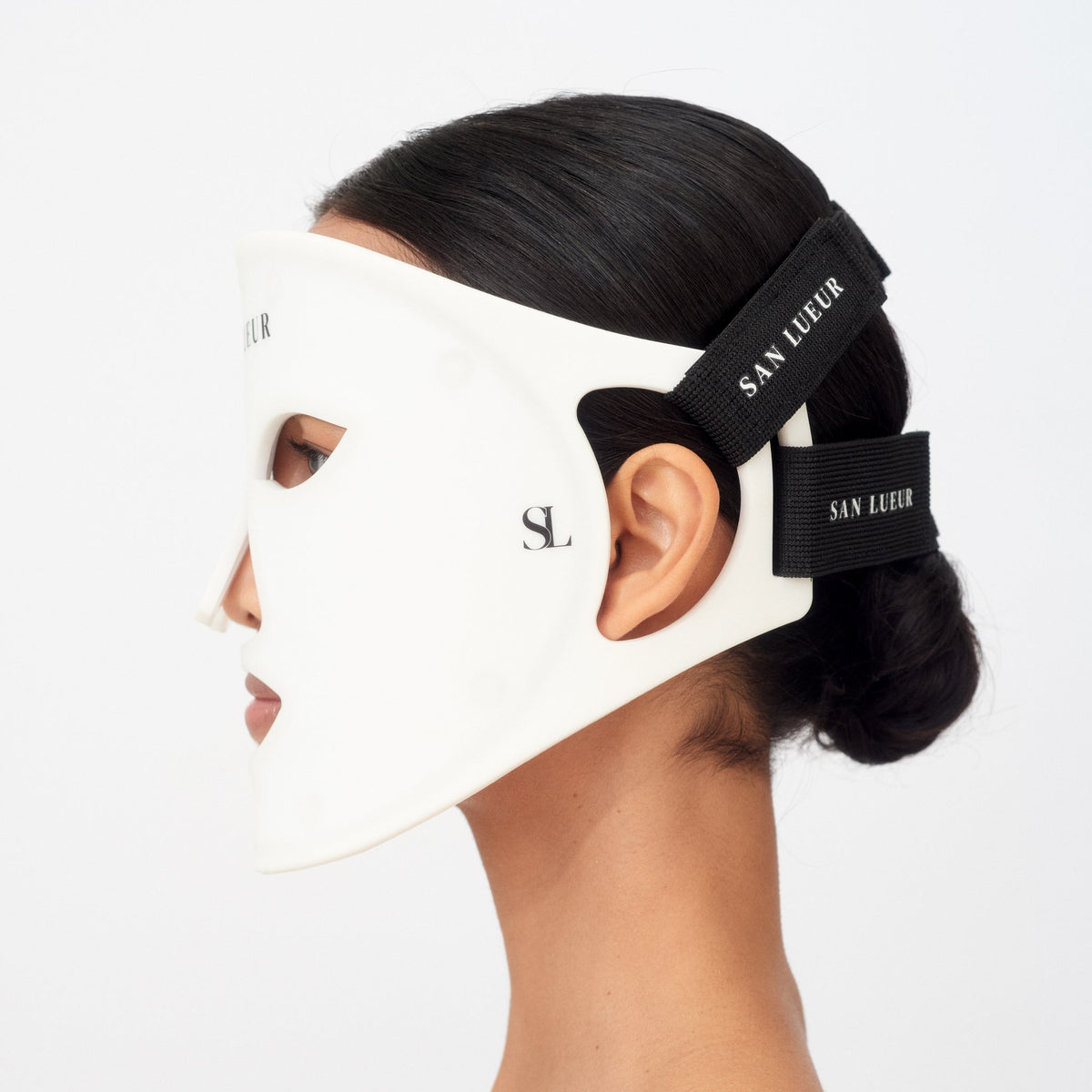 Person wearing a white face mask with black straps featuring 'San Lueur' branding.