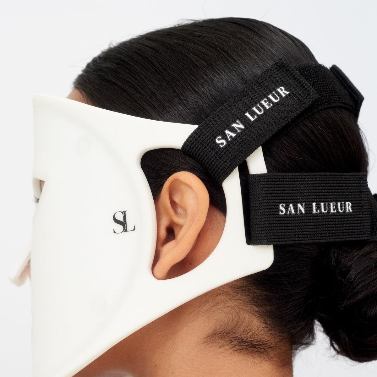 Black hair tie with 'San Lueur' branding worn by a person with their hair tied back.