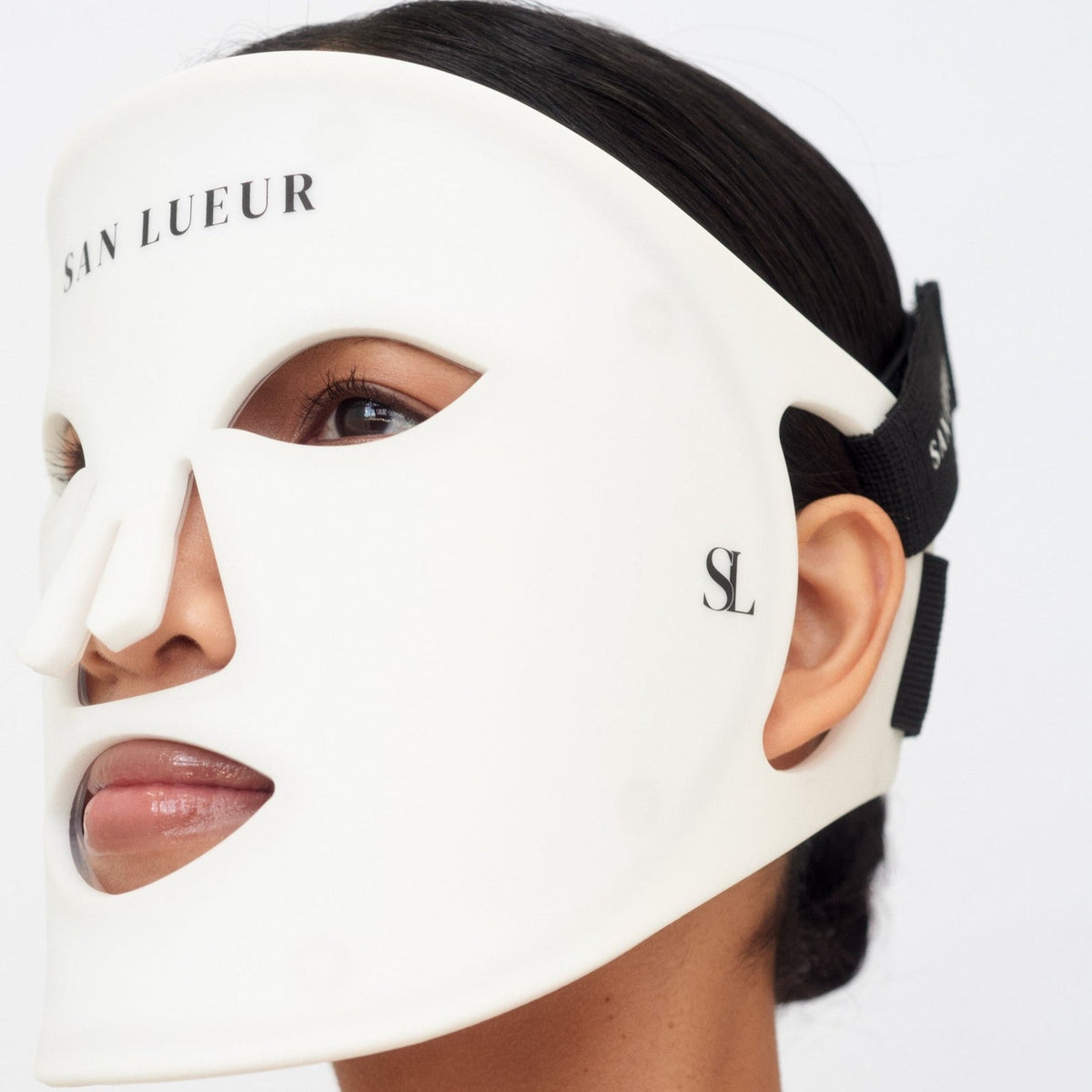 Person wearing a white face mask with 'Sain Lueur' branding on a white background