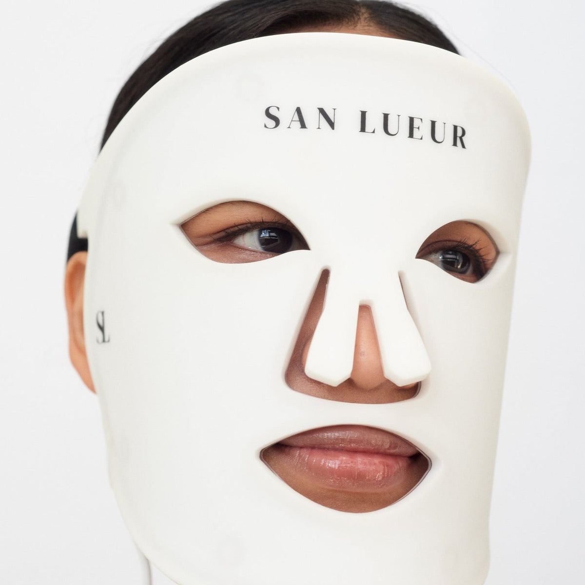 Person wearing a white face mask with 'San Lueur' branding on a white background