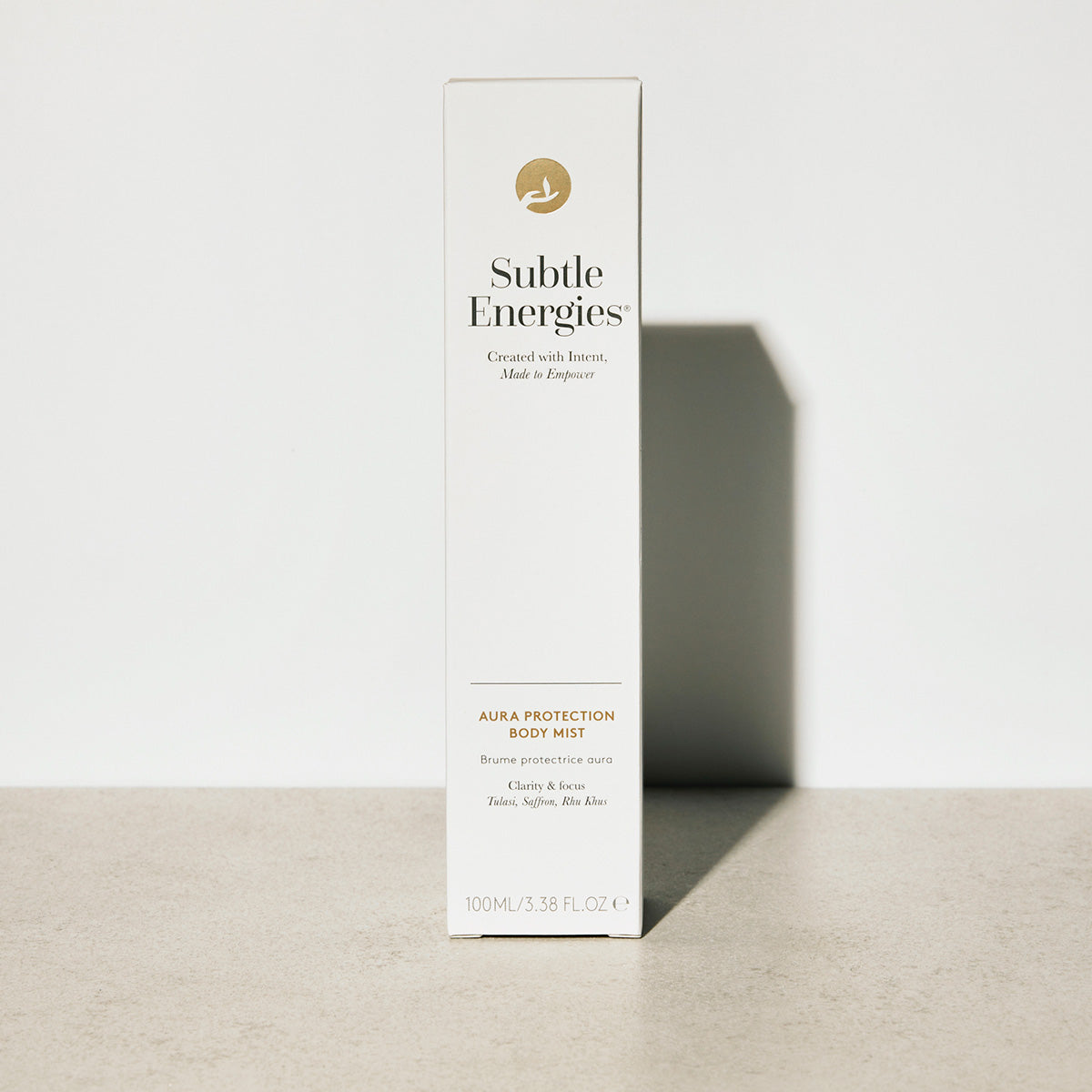 A tall, slim white box for Subtle Energies Aura & Protection Body Mist, standing upright on a light beige surface against a white background with a soft shadow.