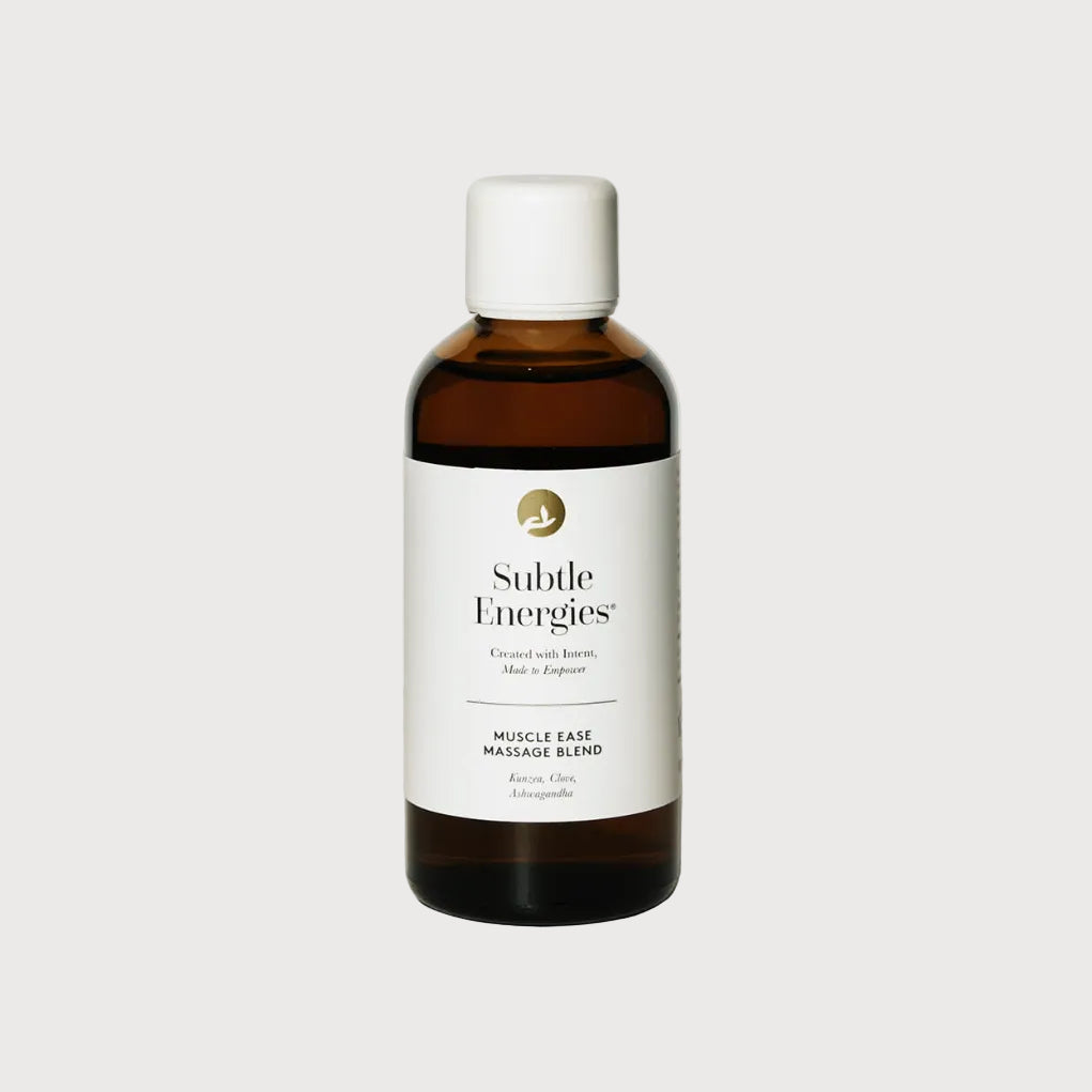 A bottle of Subtle Energies Muscle Ease Massage Blend with an amber brown glass body, white label, and white cap, set against a clean white background with a soft shadow.