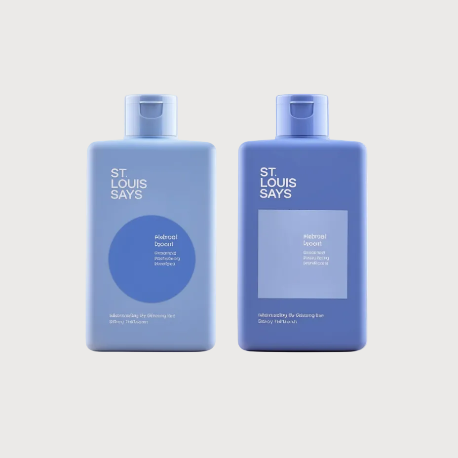 Two blue plastic bottles of St. Louis Says skincare products, one with a circular blue label and one with a rectangular label, set against a plain off-white background.