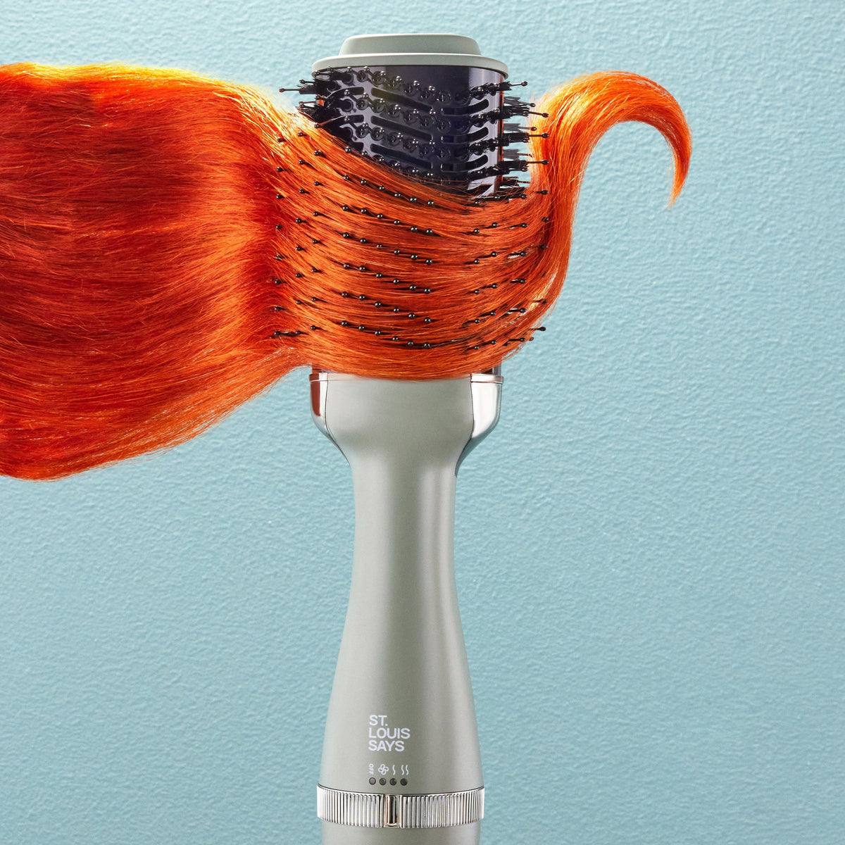 Hair dryer with orange hair on a light blue background