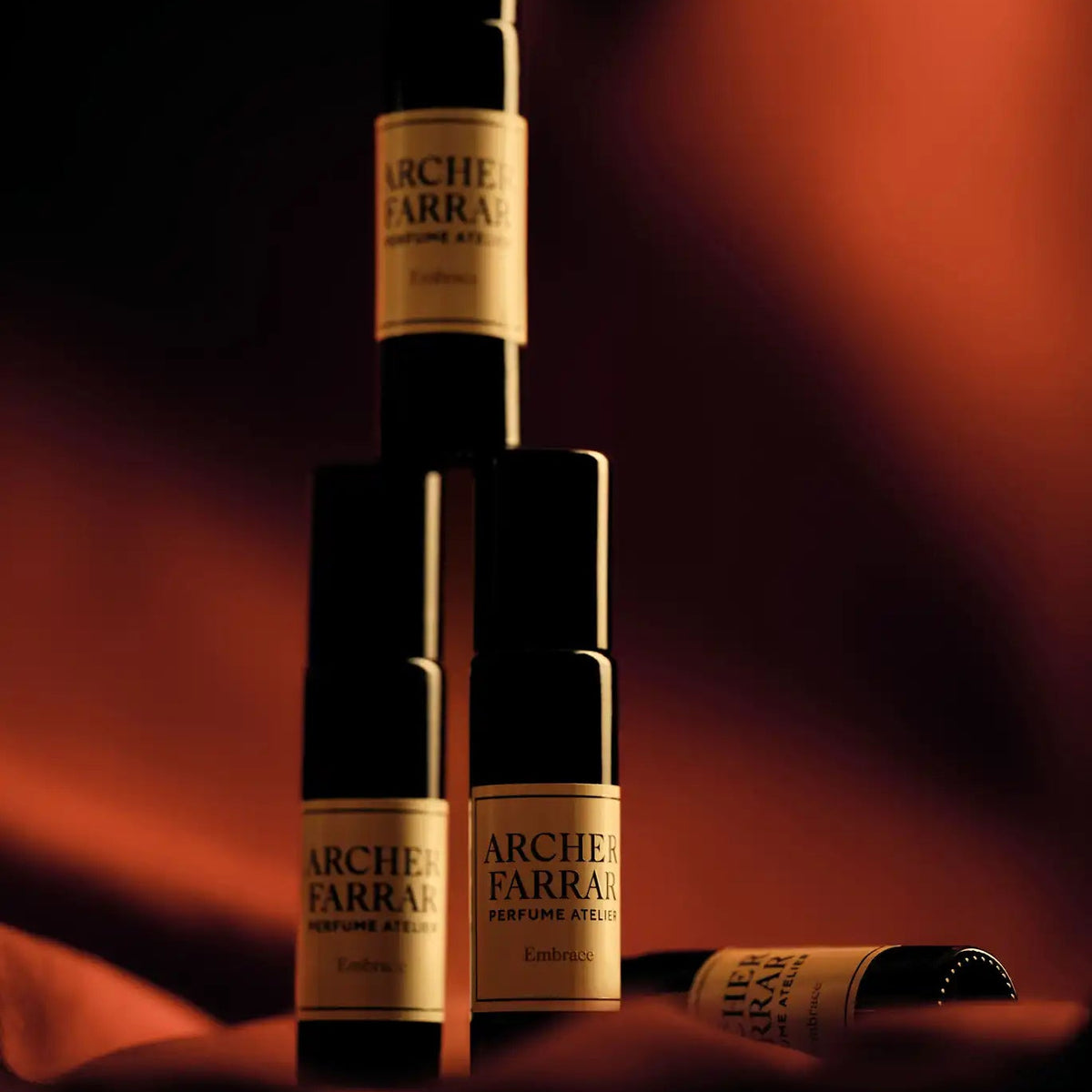 Stack of Arche Farrar perfume bottles against a warm brown background