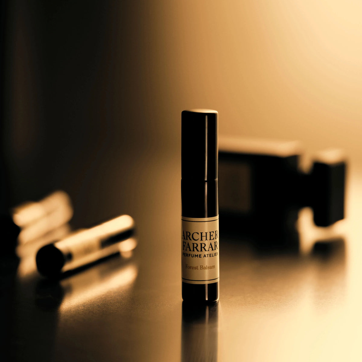 Small bottle of Archers & Farrars perfume on a reflective surface with a blurred background