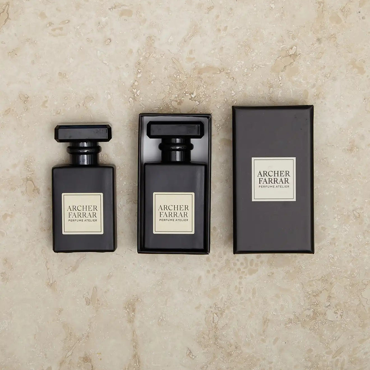 Three black perfume bottles with 'Archer Farrar' labels on a beige marble background