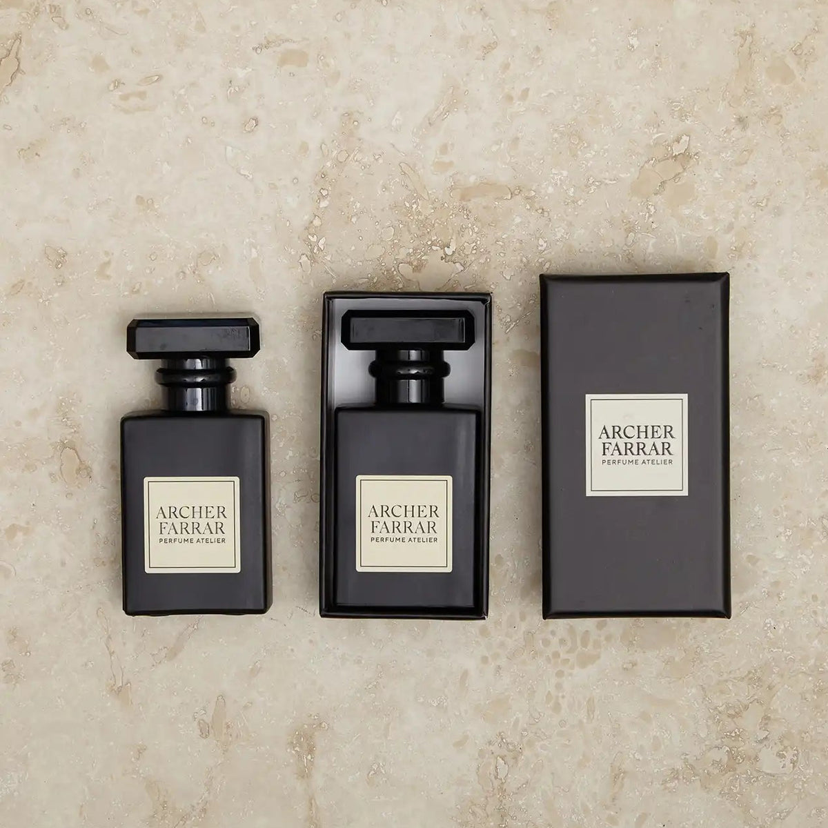 Three black perfume bottles with 'Archer Farrar' labels on a beige marble background