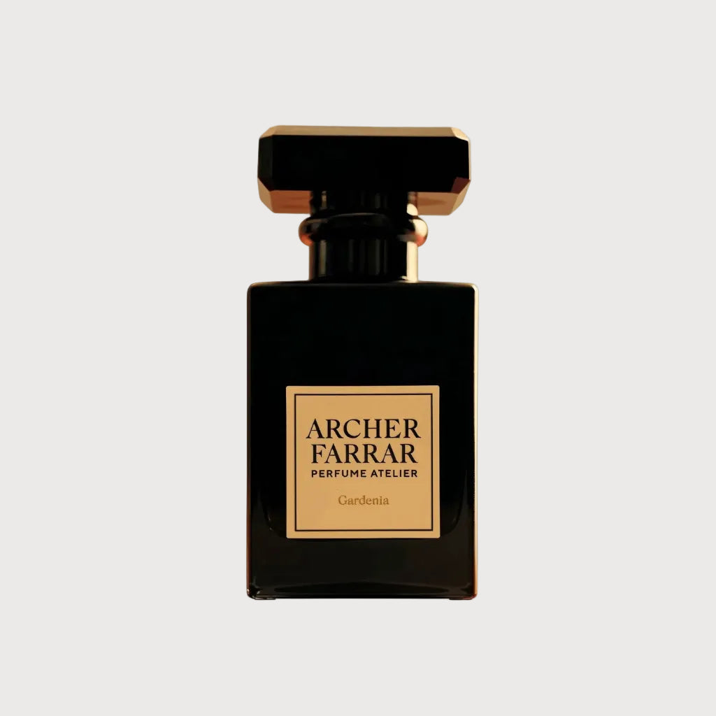 A rectangular black perfume bottle with a faceted gold cap and a gold label reading 'ARCHER FARRAR PERFUME ATELIER' and 'Gardenia' on a white background.
