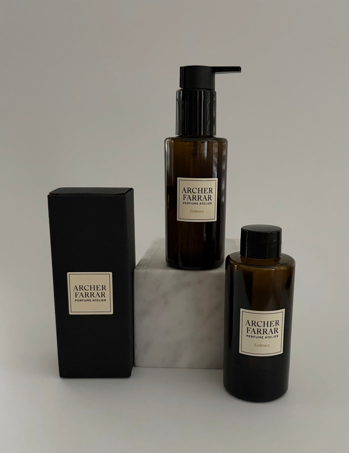 Two bottles and a box of Archer Farrar products on a light gray background