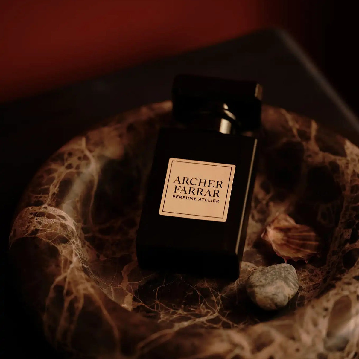 Black perfume bottle with 'Archer Farrar' label on a textured surface