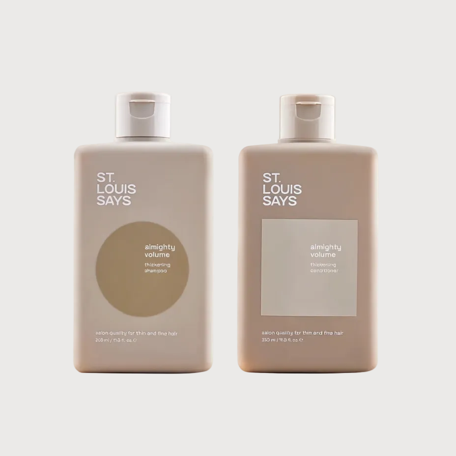 Two beige plastic bottles of St. Louis Says shampoo with white caps, displayed side-by-side against a light cream background.