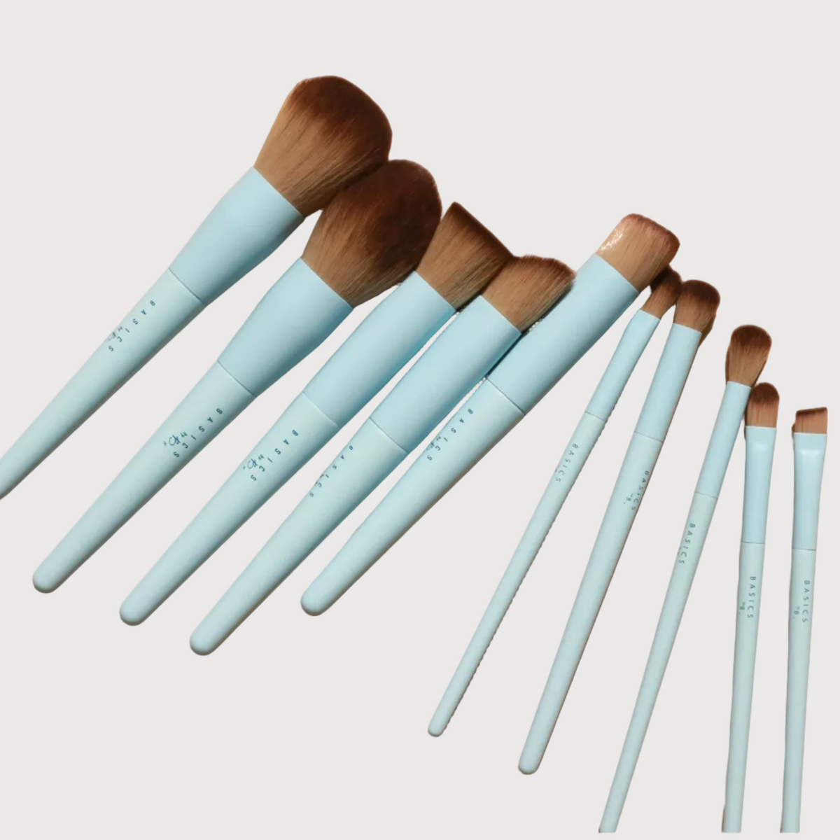 Set of makeup brushes with light blue handles on a beige background